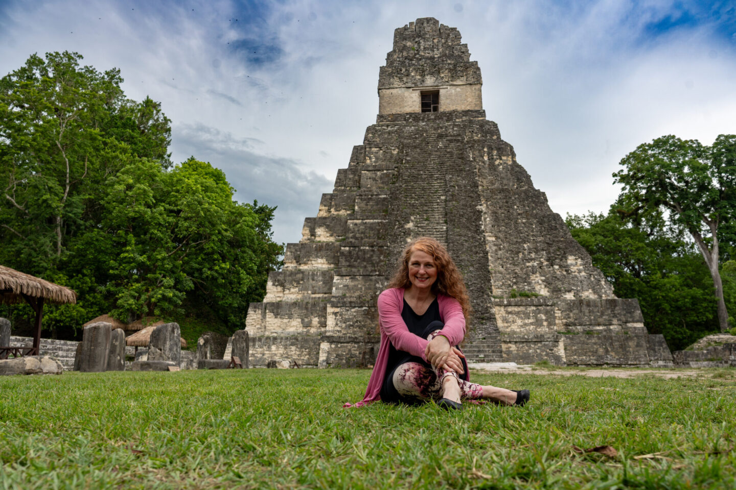 50plus female solotraveller sitting in front of a Maya temple at Tikal, Guatemala